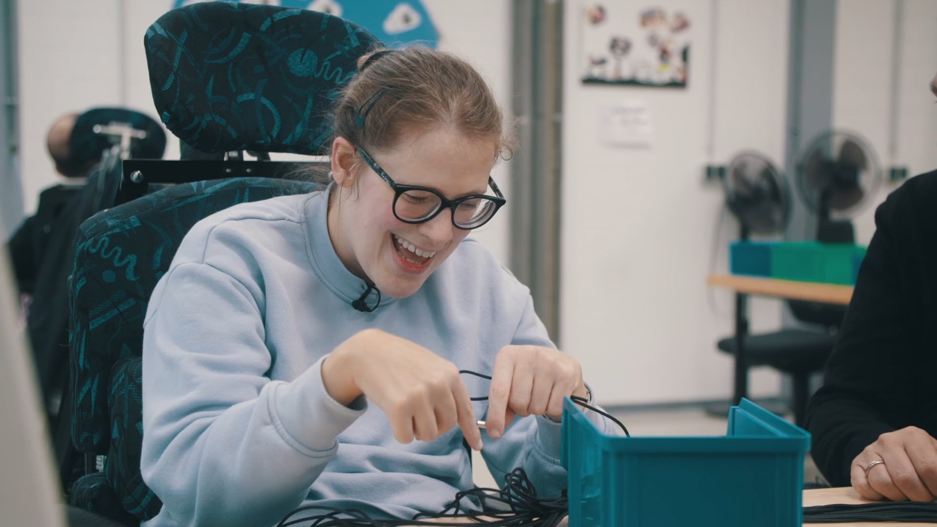 Frau mit Brille arbeitet konzentriert an einem Kabel in einer Werkstatt des Andreaswerks